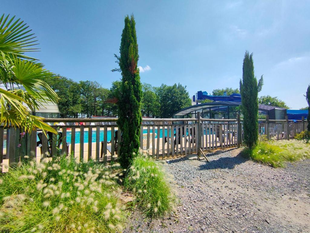 une clôture en bois avec des arbres devant une piscine dans l'établissement Mobil-home 6 pers Coeur de Vendée, à Le Pont Legé 8 autres photos
