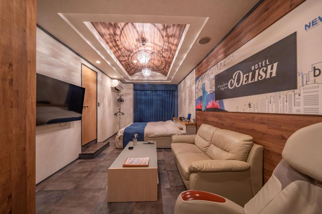 un salon avec un canapé et une télévision dans l'établissement 飛騨高山 ホテル デリッシュ, à Takayama