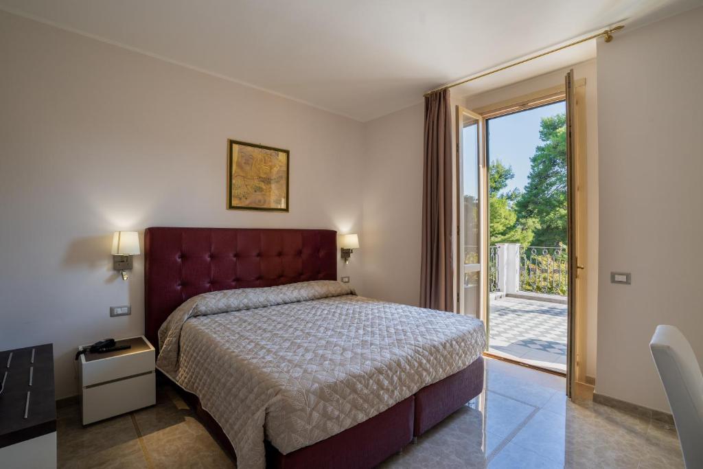 une chambre avec un lit et une porte coulissante en verre dans l'établissement Park Hotel Villa Maria, à San Menaio