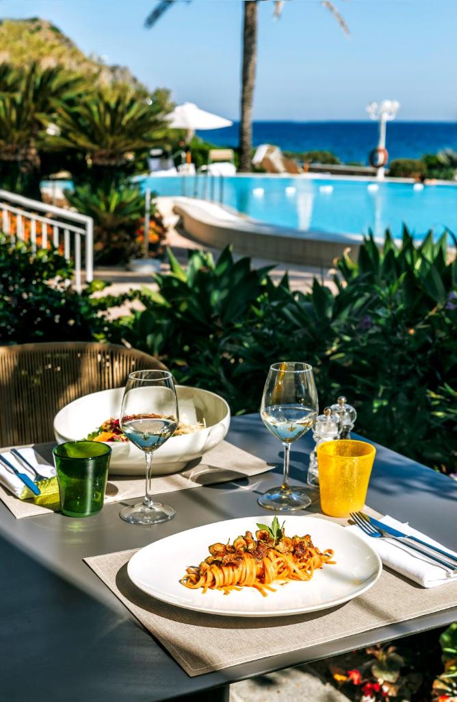 une table avec une assiette de nourriture et des verres à vin dans l'établissement Hotel Parco Smeraldo Terme, à Ischia