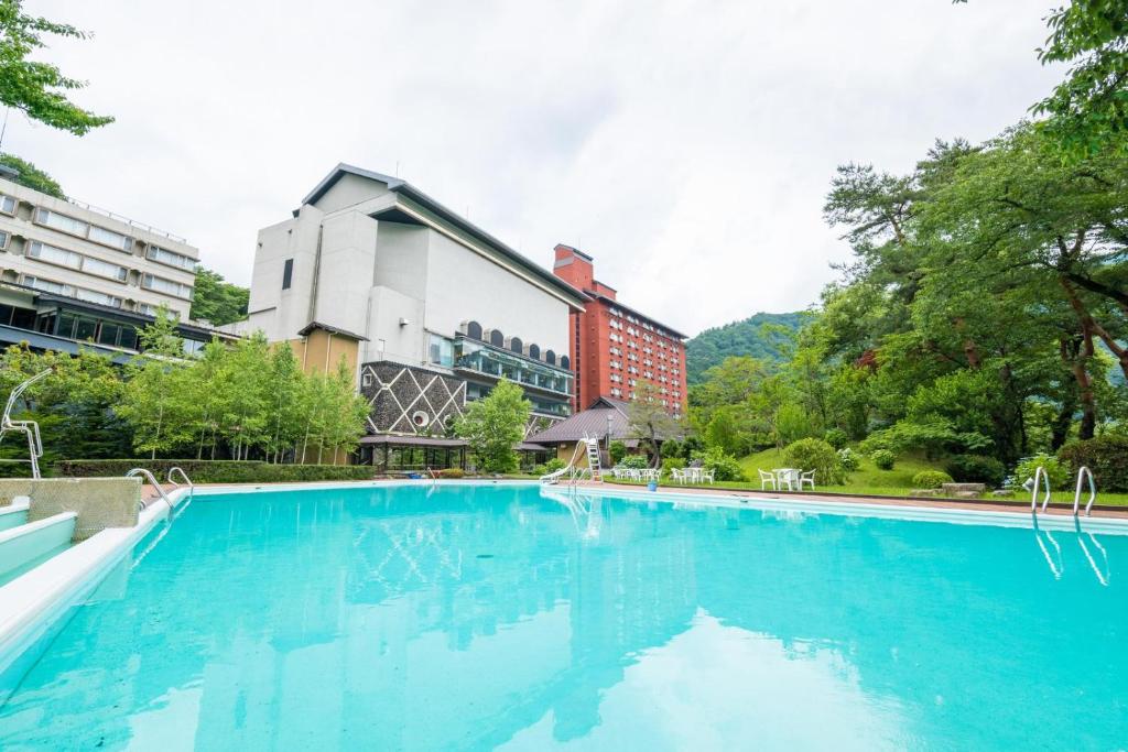 une grande piscine bleue devant un immeuble dans l'établissement Matsunoi, à Minakami