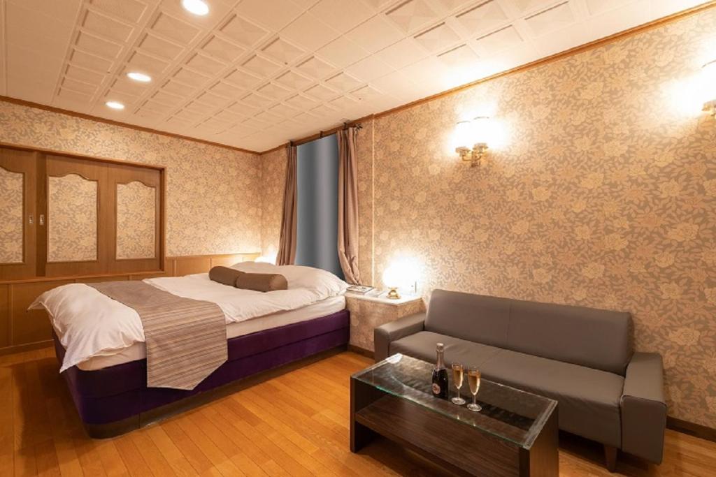 une chambre d'hôtel avec un lit et un canapé dans l'établissement プレゼントホテル チャペルガーデン 可児 ｰ大人専用ｰ, à Kani