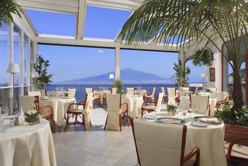 un restaurant avec tables et chaises avec vue sur l'océan dans l'établissement Grand Hotel Ambasciatori, à Sorrente