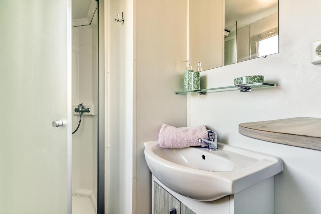 une salle de bain blanche avec un lavabo et un miroir dans l'établissement Camping maeva Club Argelès Vacances, à Argelès-sur-Mer