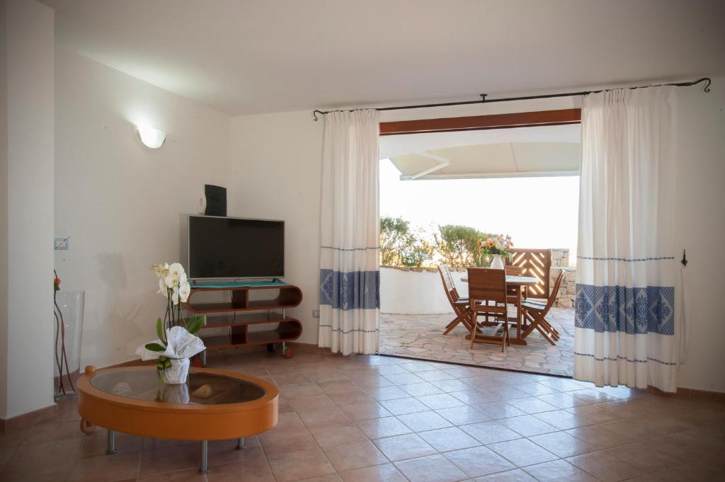 un salon avec une télévision et une table dans l'établissement Villa Isuledda Lux, à San Teodoro