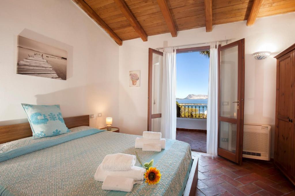 - une chambre avec un lit, des serviettes et un balcon dans l'établissement Villa Isuledda Lux, à San Teodoro