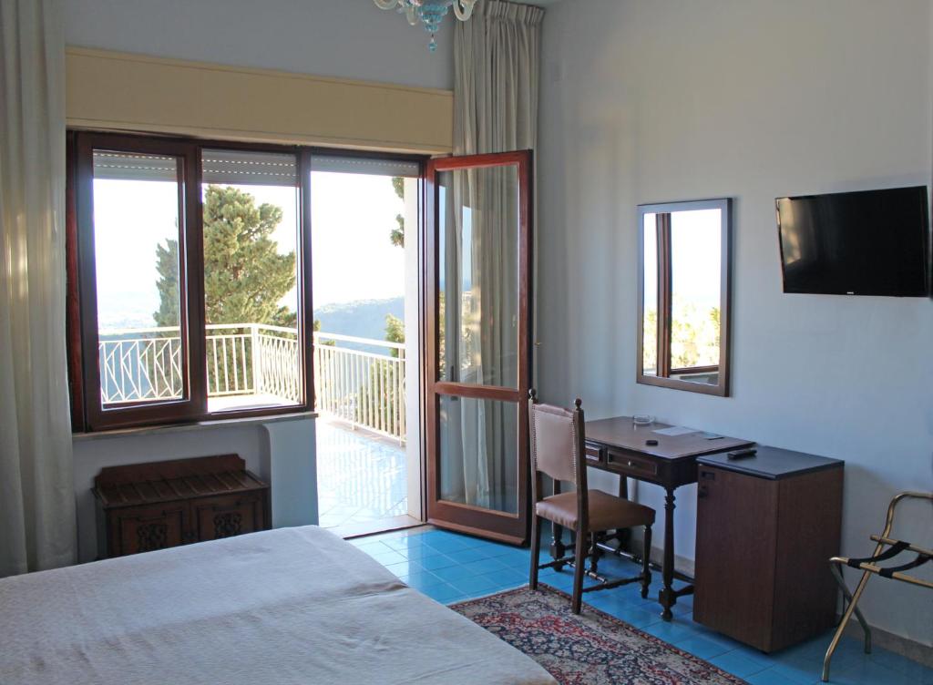 une chambre avec un lit et un bureau et un balcon dans l'établissement Hotel Mediterranée, à Taormine