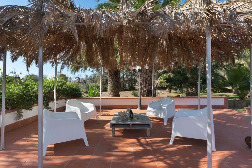 une terrasse avec des chaises blanches et une table sous un parasol dans l'établissement Villa with swimming pool Salento - Villa Le Due Sorelle, à Ugento 49 autres photos