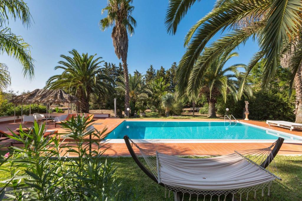 - un hamac en face d'une piscine bordée de palmiers dans l'établissement Villa with swimming pool Salento - Villa Le Due Sorelle, à Ugento
