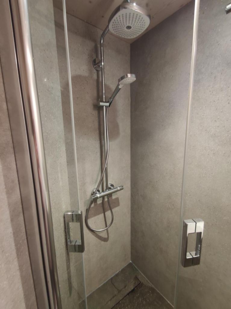 une douche dans une salle de bain avec une porte vitrée dans l'établissement Douglas - Appartement au cœur du Jardin Alpin, à Courchevel