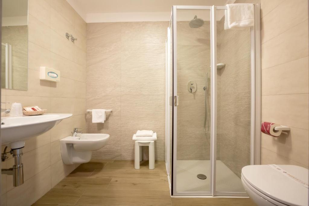 une salle de bain avec douche, lavabo et toilettes dans l'établissement Hotel Montreal, à Bibione