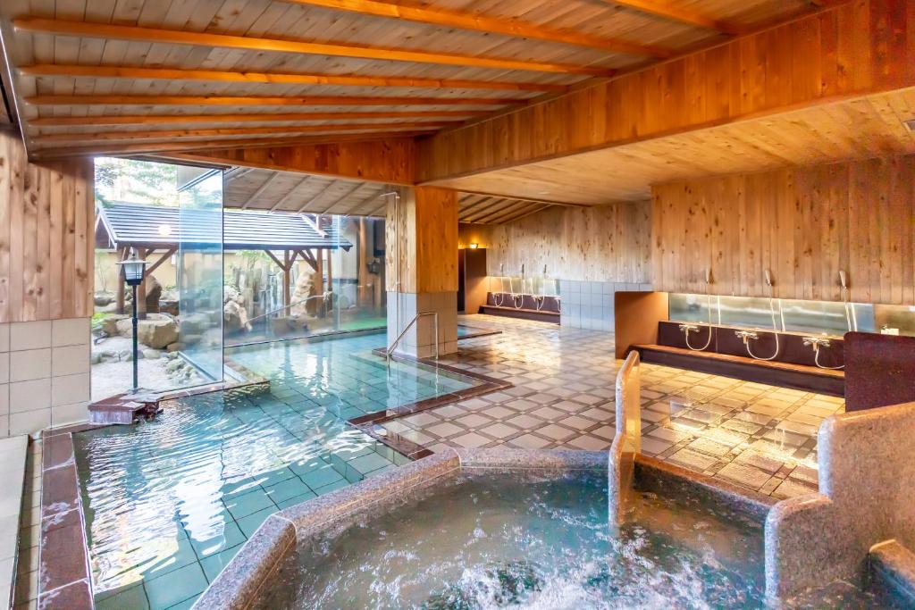 une piscine intérieure avec un bain à remous dans une maison dans l'établissement Hotel Keisui, à Omachi