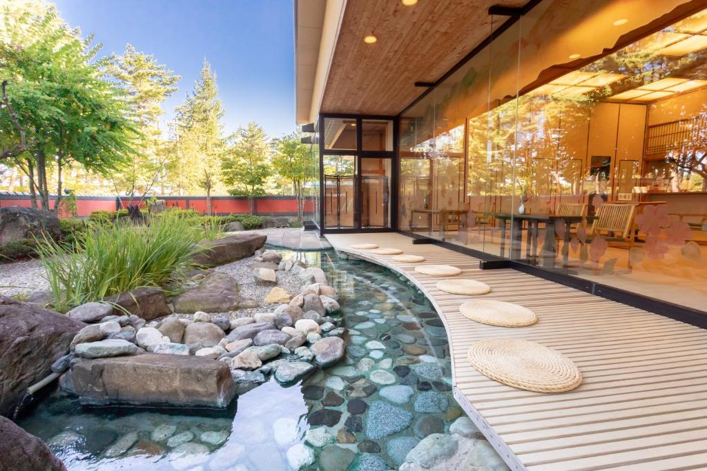 une maison avec un étang devant un immeuble dans l'établissement Hotel Keisui, à Omachi