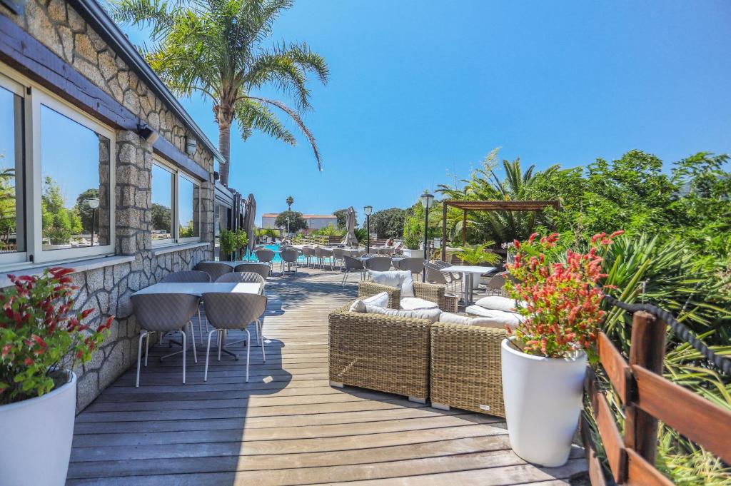une terrasse avec des tables, des chaises et des palmiers dans l'établissement Camping maeva Escapades Colomba, à Olmeto