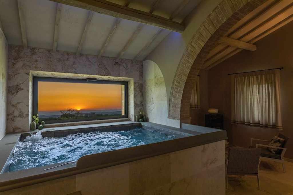une grande baignoire dans une pièce avec une grande fenêtre dans l'établissement Villa I Cipressini piscina riscaldata spa Toscana, à Pienza