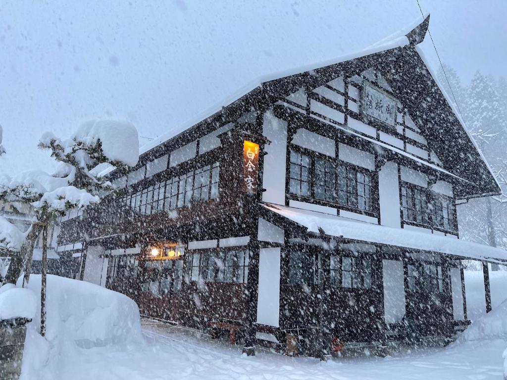 un grand bâtiment recouvert de neige avec une lumière dans l'établissement Yadoya Shiroganeya Limited to one group per day (2 to 8 people) Fully booked traditional building inn Traditional culture experience, à Nagano