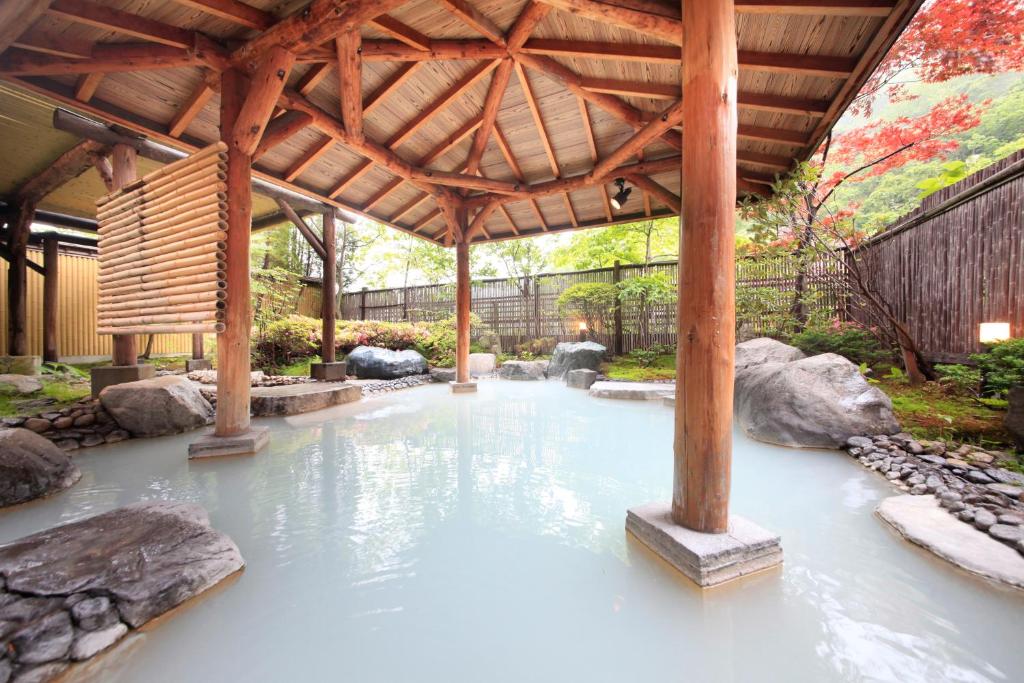 un bassin d'eau sous une pergola en bois dans l'établissement Ryotei Hanayura, à Noboribetsu