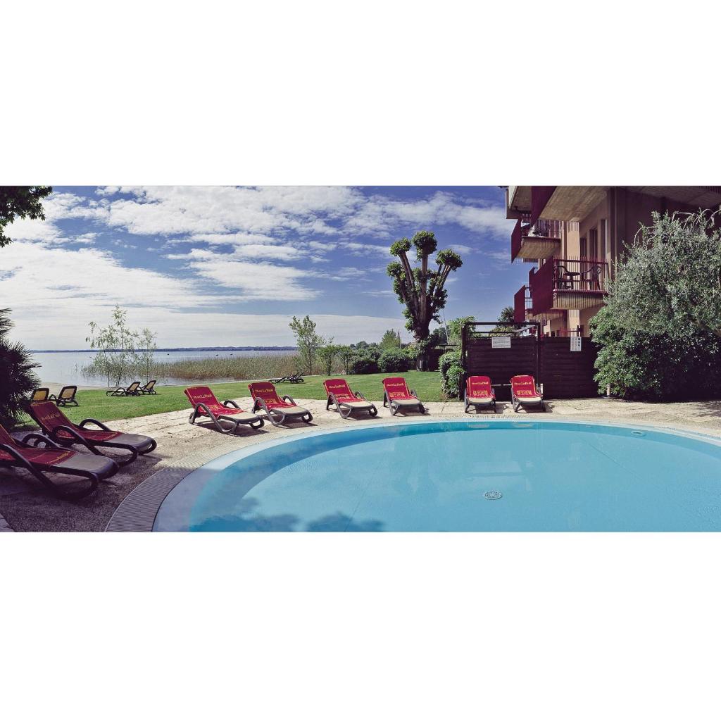 - une piscine avec des chaises longues et un groupe dans l'établissement Hotel Smeraldo, à Sirmione