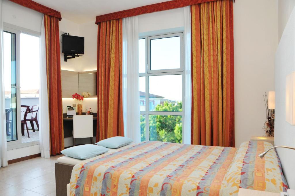 une chambre avec un lit et une grande fenêtre dans l'établissement Hotel Venezia, à Caorle 176 autres photos