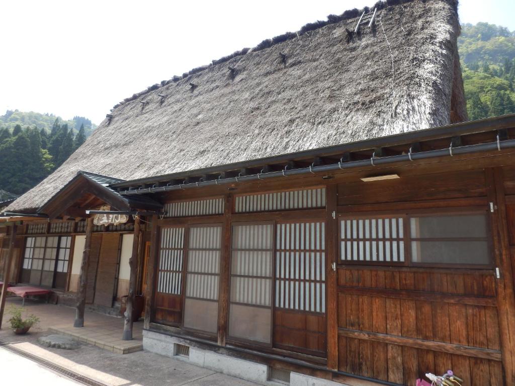 - un bâtiment ancien avec un toit de chaume et des portes dans l'établissement Minshuku Goyomon, à Nanto