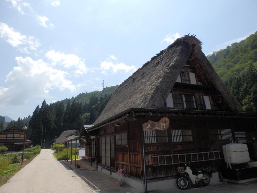 un bâtiment au toit de chaume avec une moto garée devant dans l'établissement Minshuku Goyomon, à Nanto