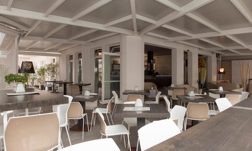 une salle à manger avec des tables et des chaises blanches dans l'établissement Hotel Helvetia, à Lido di Jesolo