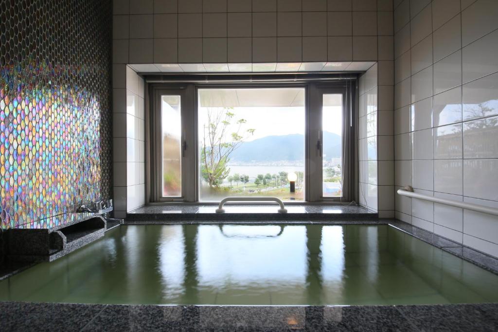 La salle de bains est pourvue d'une piscine d'eau et d'une fenêtre. dans l'établissement Rako Hananoi Hotel, à Suwa