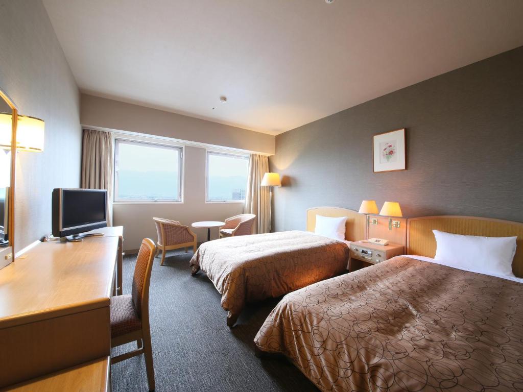 une chambre d'hôtel avec deux lits et un bureau dans l'établissement Rako Hananoi Hotel, à Suwa