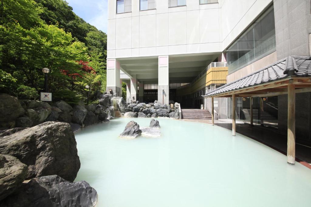 une rivière avec des rochers devant un bâtiment dans l'établissement Hotel Mahoroba, à Noboribetsu