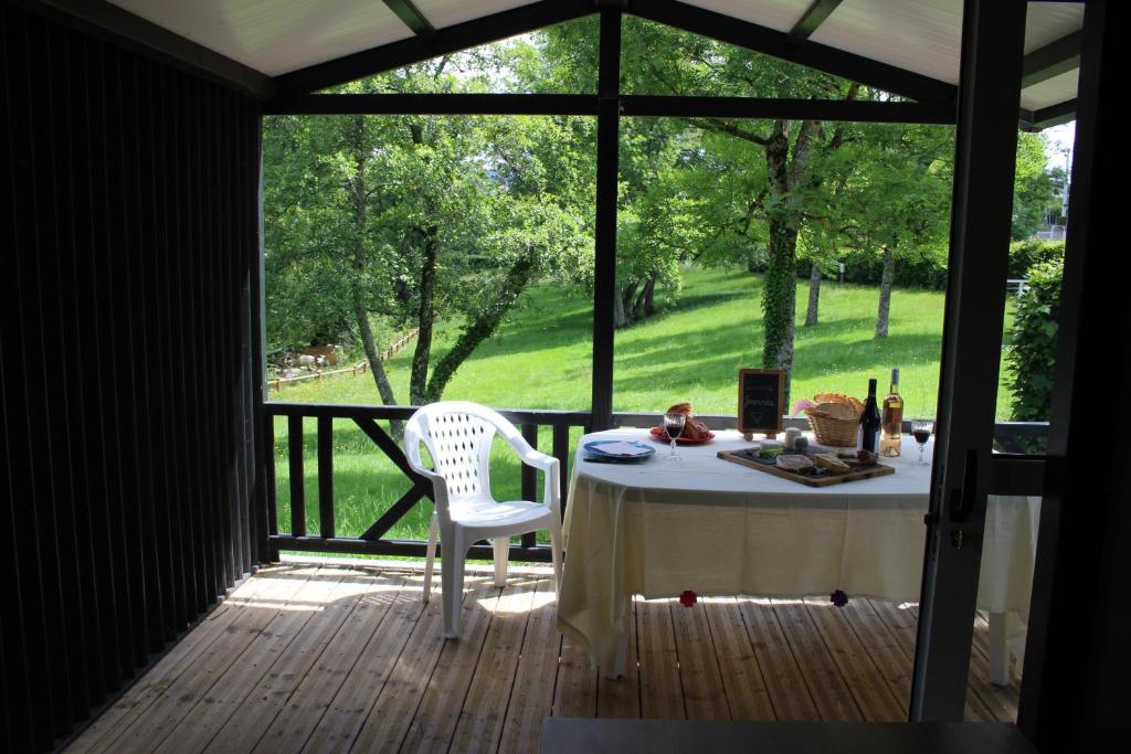 - une table et une chaise sur une terrasse couverte avec une fenêtre dans l'établissement Camping Les Feuilles Chauffailles, à Chauffailles