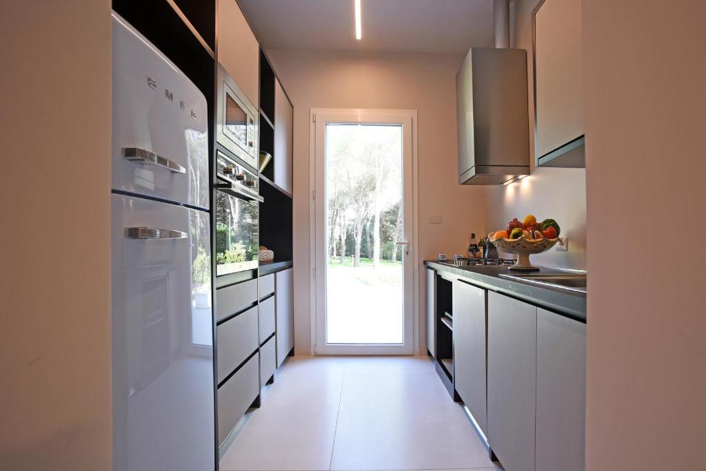 une cuisine avec des placards blancs et une porte donnant sur une cour. dans l'établissement Nerodavola by PosarelliVillas, à San Corrado di Fuori