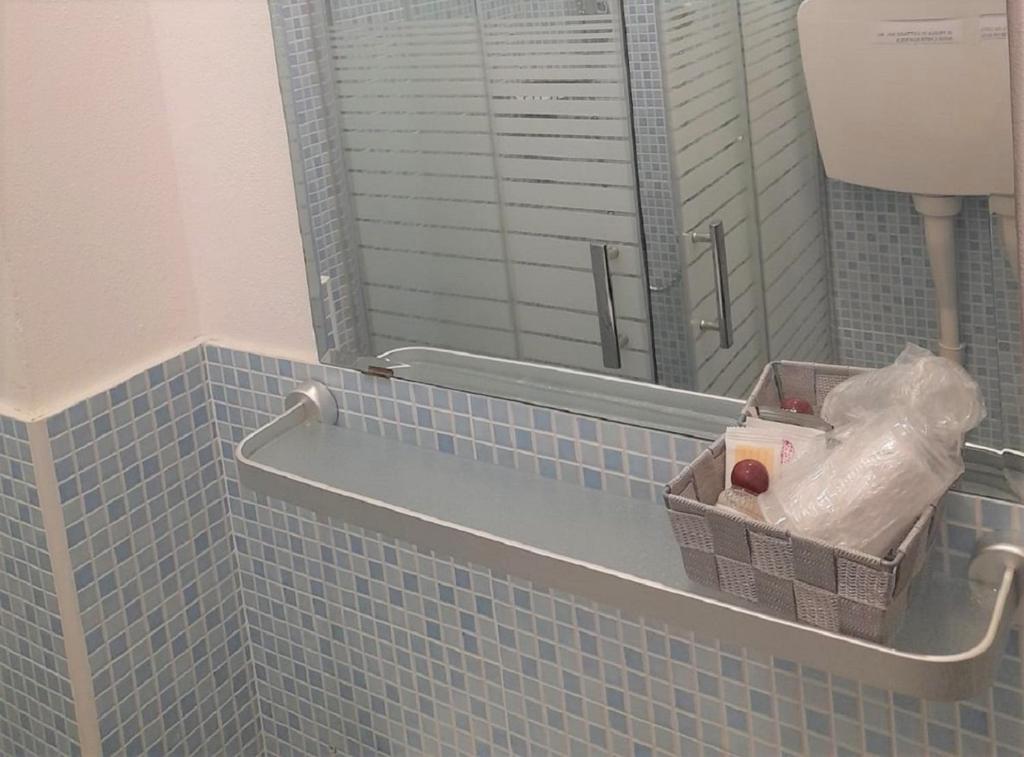 une salle de bain avec un miroir et un mur carrelé bleu dans l'établissement Hotel Enrica, à Cervia