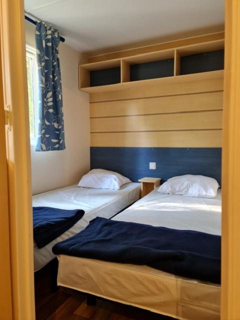 - 2 lits dans une petite chambre aux murs bleus dans l'établissement MOBIL HOME familiale EN ALSACE11 KM DES GRANDS PARCS, à Boofzheim
