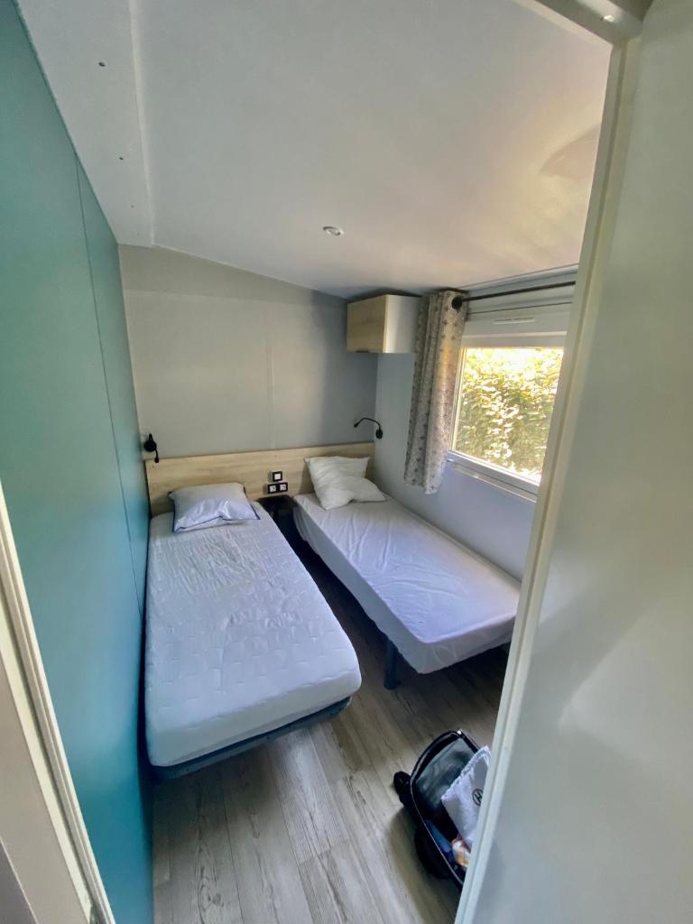 deux lits dans une petite pièce avec une fenêtre dans l'établissement Mobilhome 6 places vue mer, à Drammont 3 autres photos