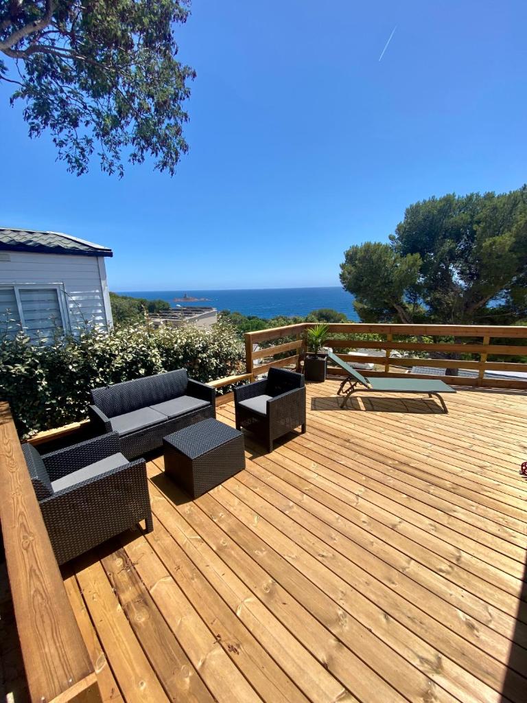 une terrasse en bois avec des canapés et des chaises. dans l'établissement Mobilhome 6 places vue mer, à Drammont
