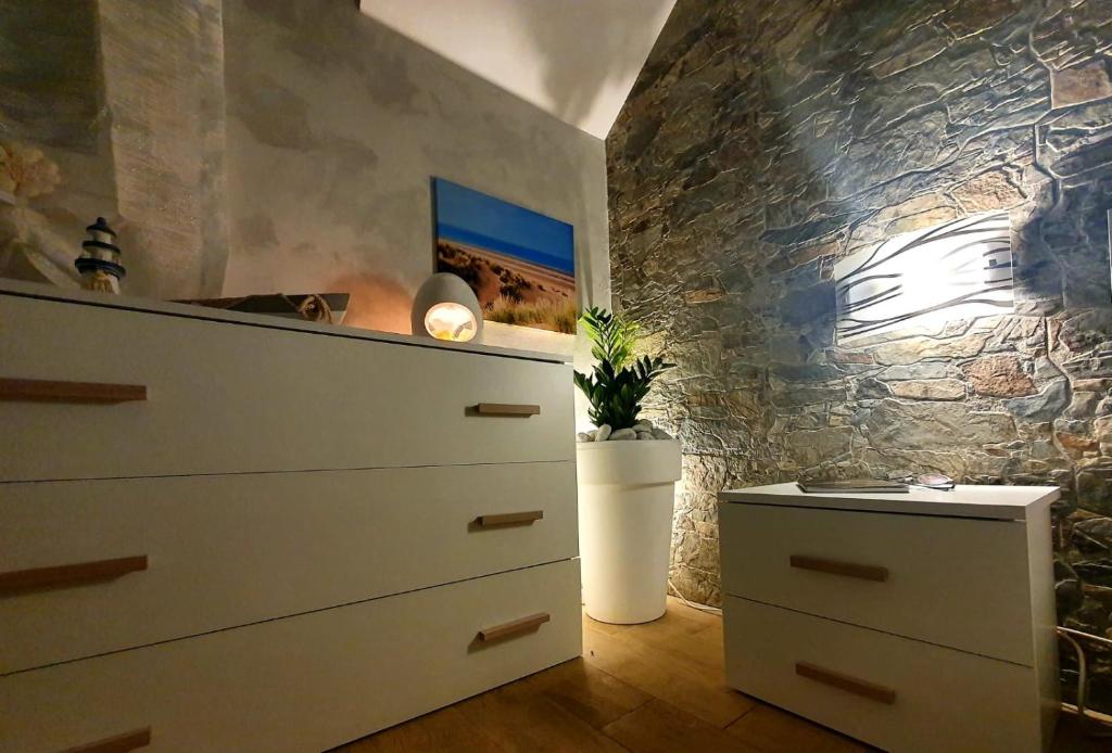 - une chambre avec une commode et un mur en pierre dans l'établissement La Perla di Marzamemi, à Marzamemi 111 autres photos