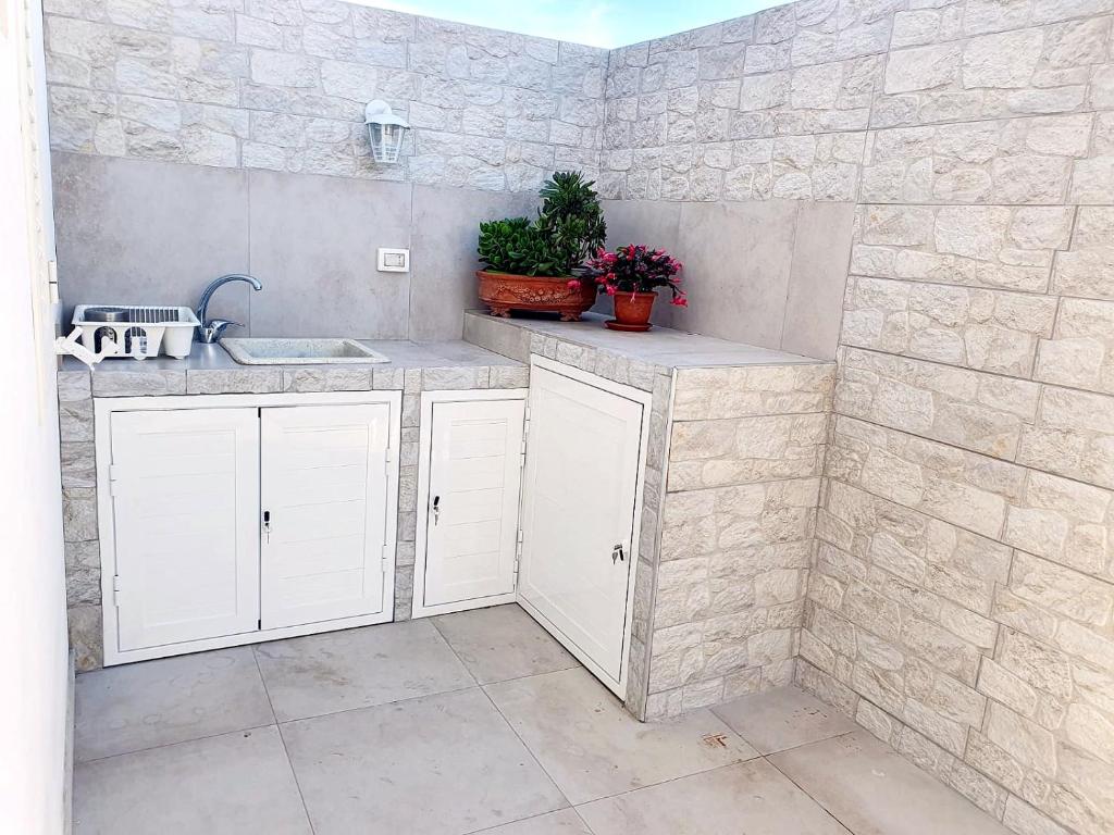 une cuisine avec des armoires blanches et un évier dans l'établissement La Perla di Marzamemi, à Marzamemi