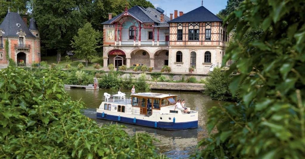 un bateau dans l'eau devant une grande maison dans l'établissement Kuhnle-Tours Niderviller, à Niderviller