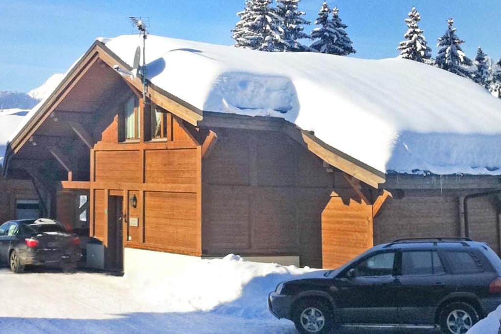 une maison recouverte de neige avec une voiture garée devant dans l'établissement chalet Amitie familial de luxe avec JACUZZI, HEBERGEMENT MULTIPASS ETE, WIFI fibre, 150 m des pistes de ski et randonnées, aux Gets