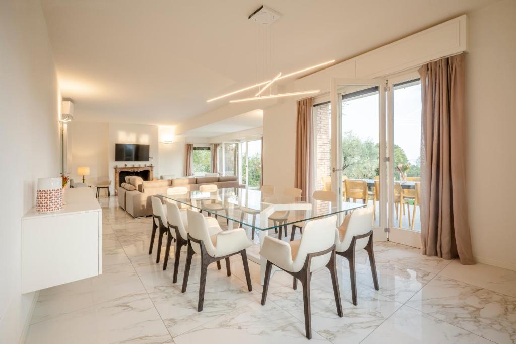 - une salle à manger et un salon avec une table et des chaises en verre dans l'établissement Villa dei Lauri - villa vista lago con piscina, à Salò