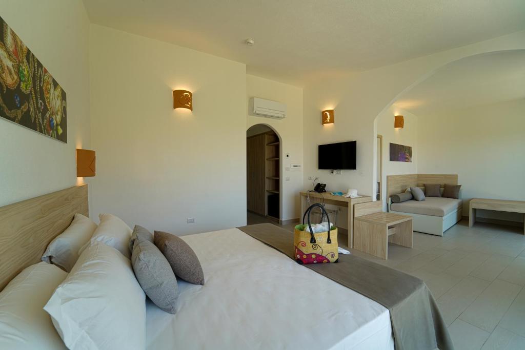 - une chambre avec un lit blanc et un salon dans l'établissement GH Santina Resort & SPA, à Valledoria
