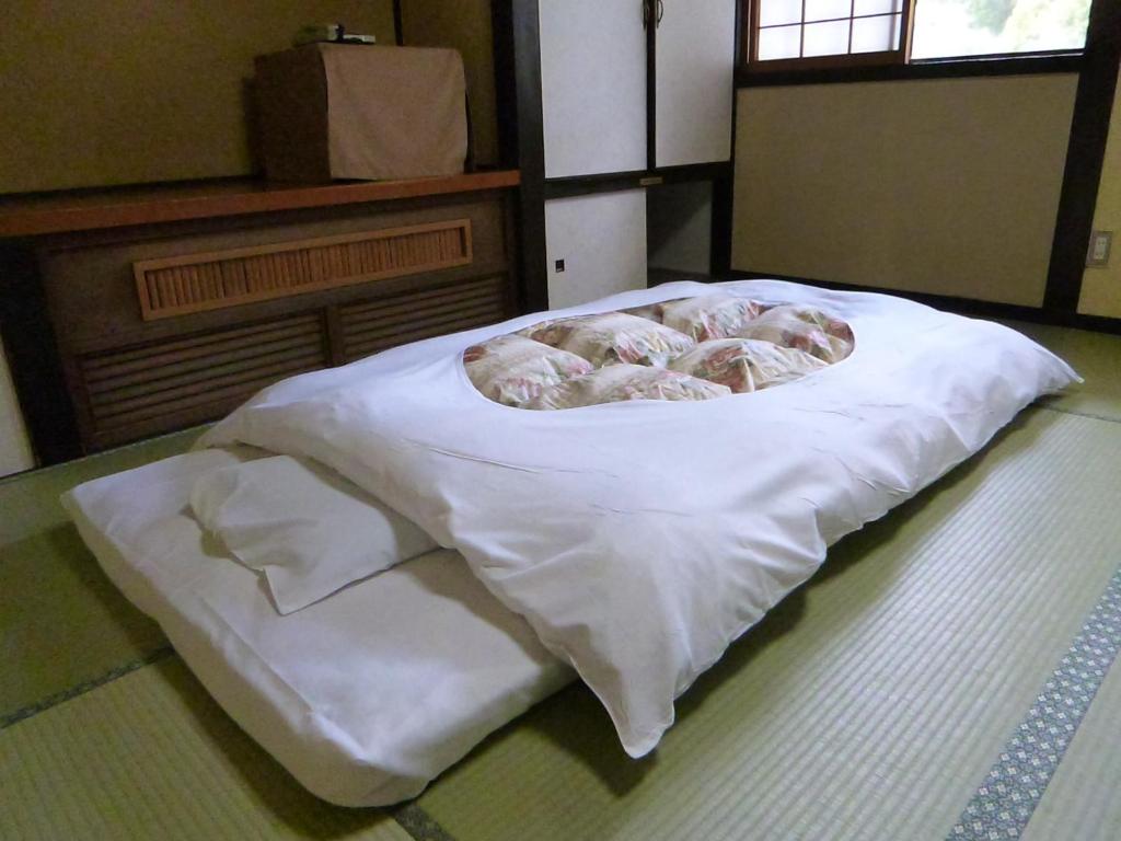 - un lit avec des draps blancs et des beignets dans l'établissement Iwamura Sanso, à Ena 36 autres photos