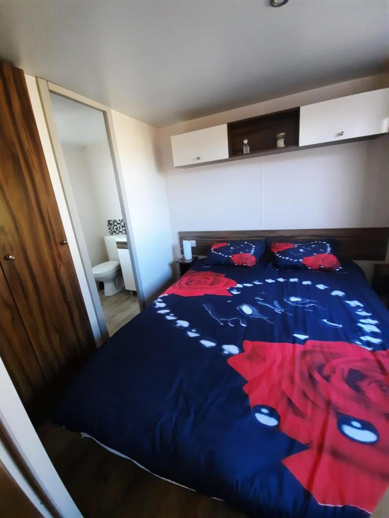 - une chambre avec un lit bleu orné de fleurs rouges dans l'établissement Grand mobilhome spacieux 8 places frejus/straphael, à Fréjus 31 autres photos