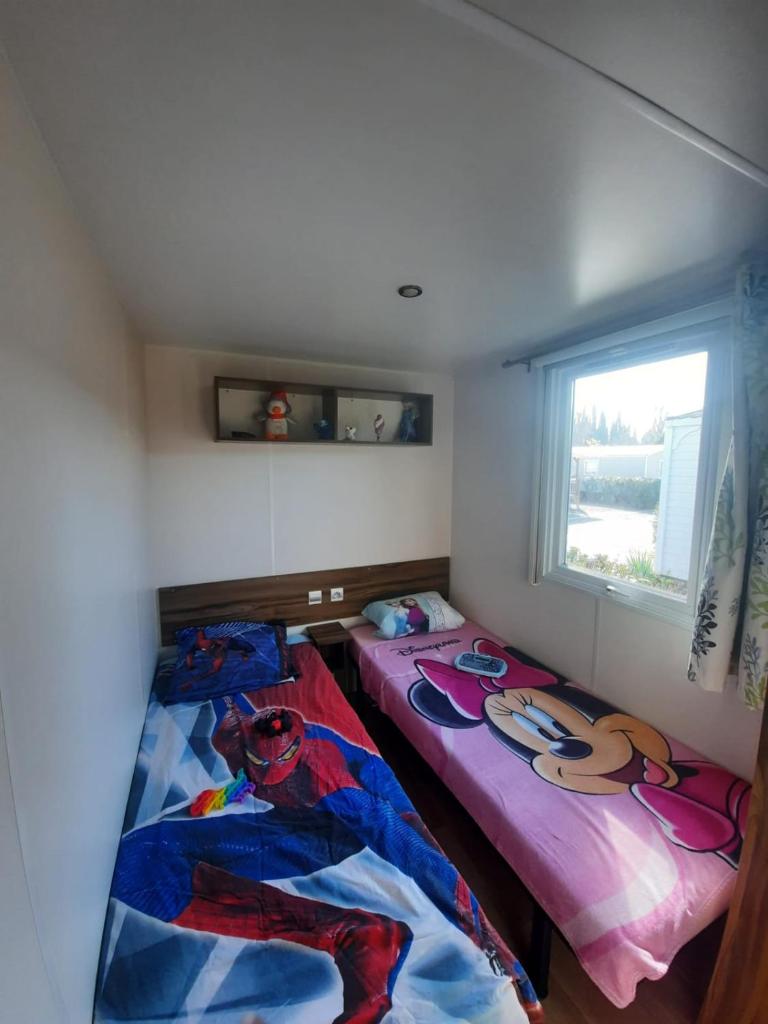 deux lits dans une petite pièce avec une fenêtre dans l'établissement Grand mobilhome spacieux 8 places frejus/straphael, à Fréjus