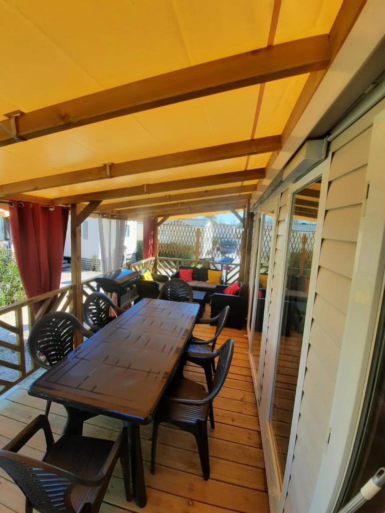 une table et des chaises en bois sur une terrasse dans l'établissement Grand mobilhome spacieux 8 places frejus/straphael, à Fréjus