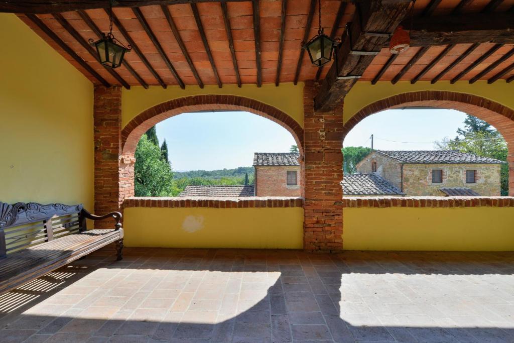 un patio extérieur avec deux arches et un banc dans l'établissement Casale le Rondini by VacaVilla, à Lucignano 33 autres photos
