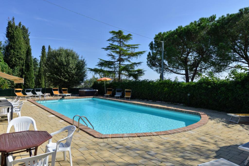 une piscine avec des chaises et une table dans l'établissement Casale le Rondini by VacaVilla, à Lucignano