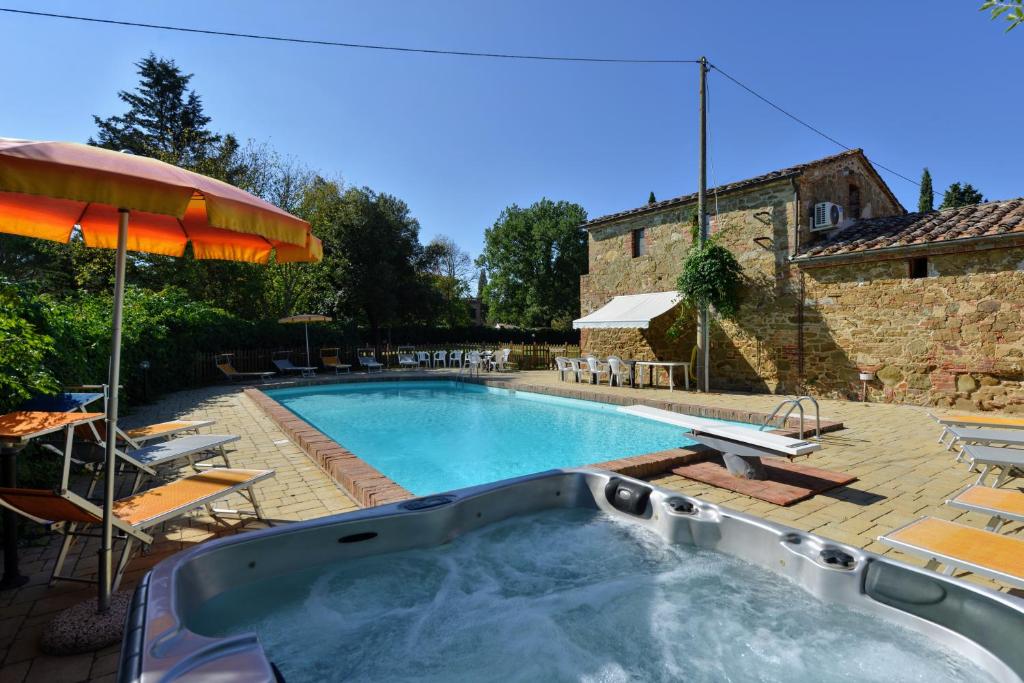 une grande piscine avec un parasol et des chaises dans l'établissement Casale le Rondini by VacaVilla, à Lucignano