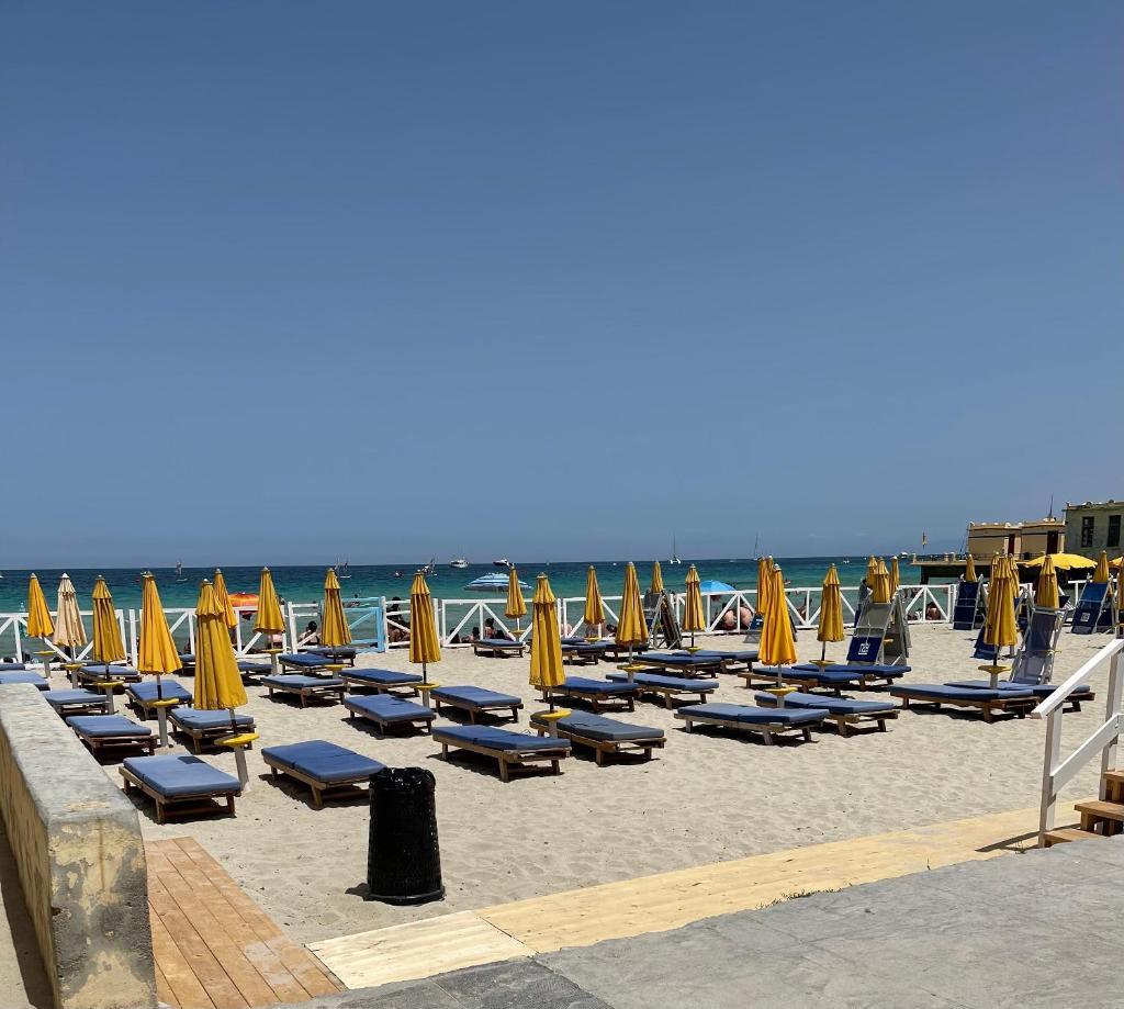 une plage avec des chaises et des parasols et l'océan dans l'établissement Villa Calipso, à Mondello