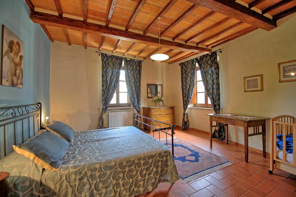 une chambre avec un lit, un bureau et des fenêtres dans l'établissement Villa Capolona by PosarelliVillas, à Calbenzano